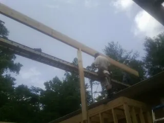 Carpenter setting a ridge beam over a new addition frame — Ice Dam Removal by Roofing Brothers in Stafford Springs