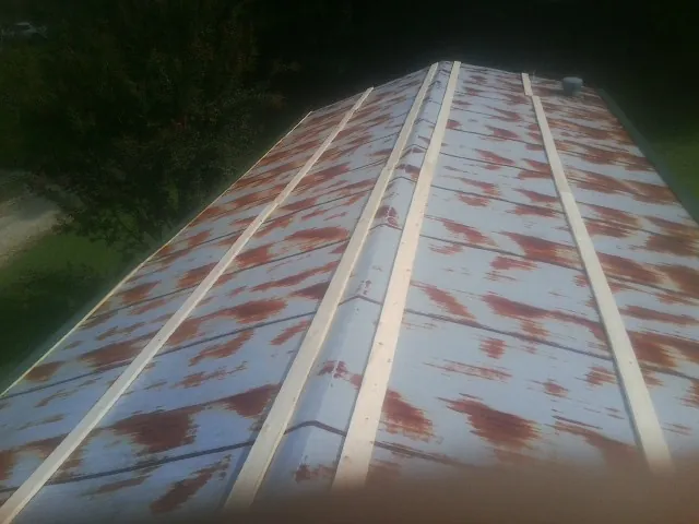Rusted metal roof panels with new wood purlins before replacement — Storm Damage Roof Repair in Stafford Springs by Roofing Brothers