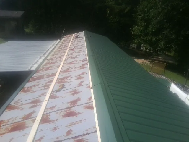 Old rusted panels beside newly installed green metal roofing — Wind Damage Roof Repair by Roofing Brothers in Stafford Springs