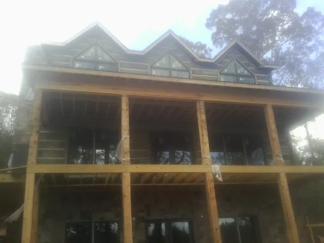 Dormers and porch framing on a large log home under construction — Roof Coating work by our crew in Stafford Springs