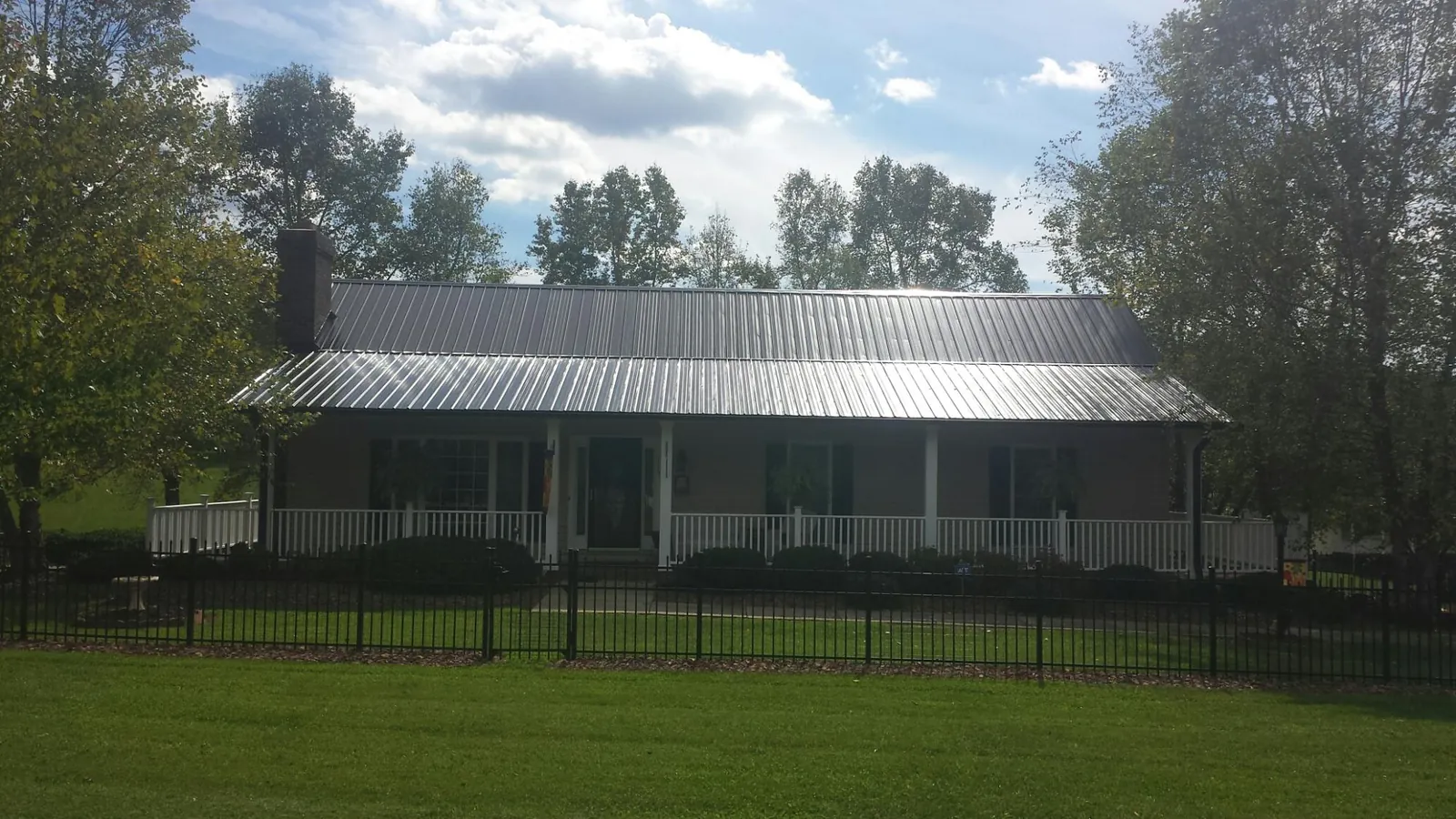 Gray metal roof on a brick ranch with a full width front porch — Gutter Guard Installation work by our crew in Stafford Springs
