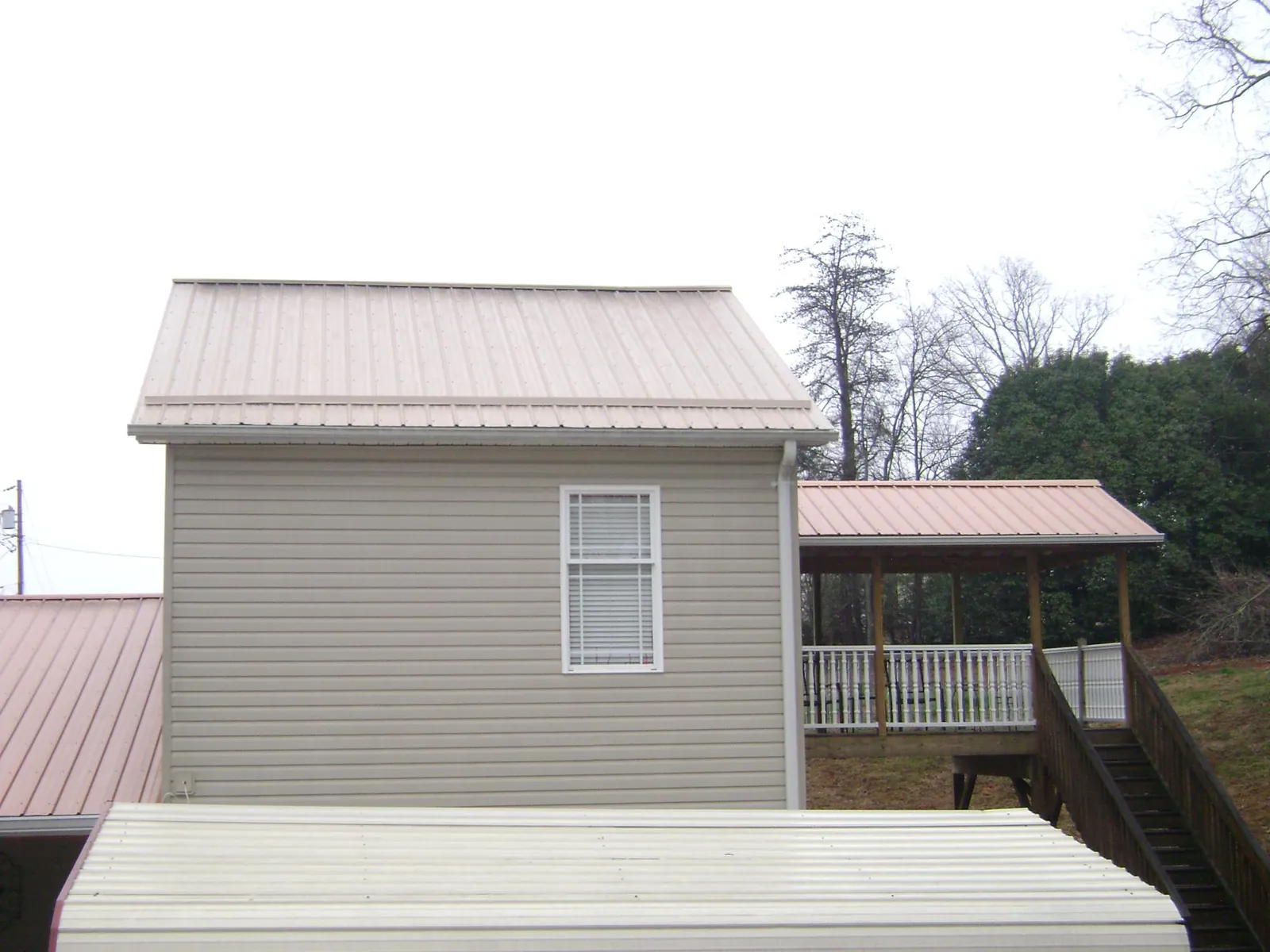 Tan metal roofs on a two story addition and attached porch, from a Roof Replacement job in Stafford Springs