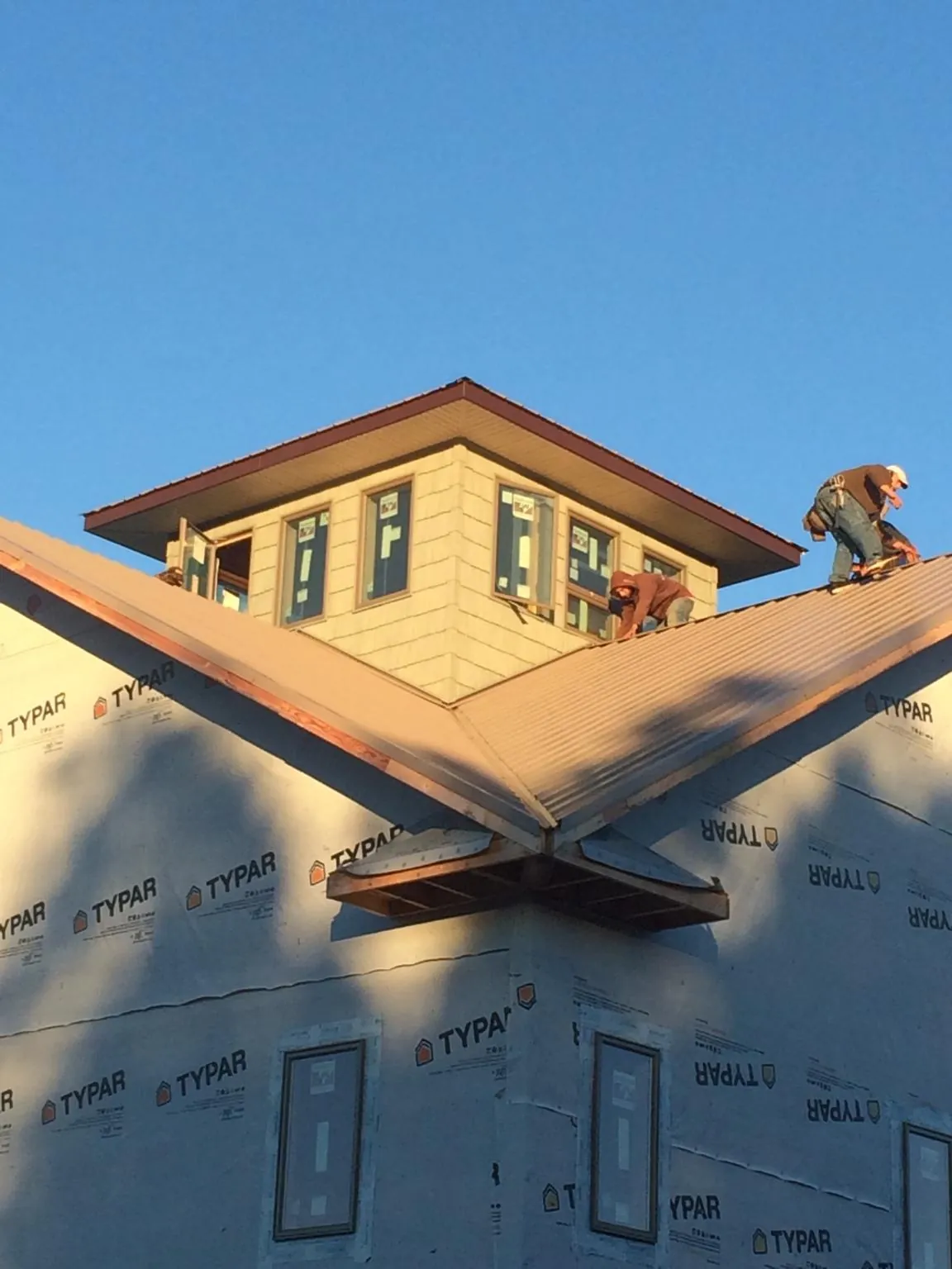 Roofers working around a rooftop cupola on a new metal roof at sunset — Roof Waterproofing in Stafford Springs by Roofing Brothers